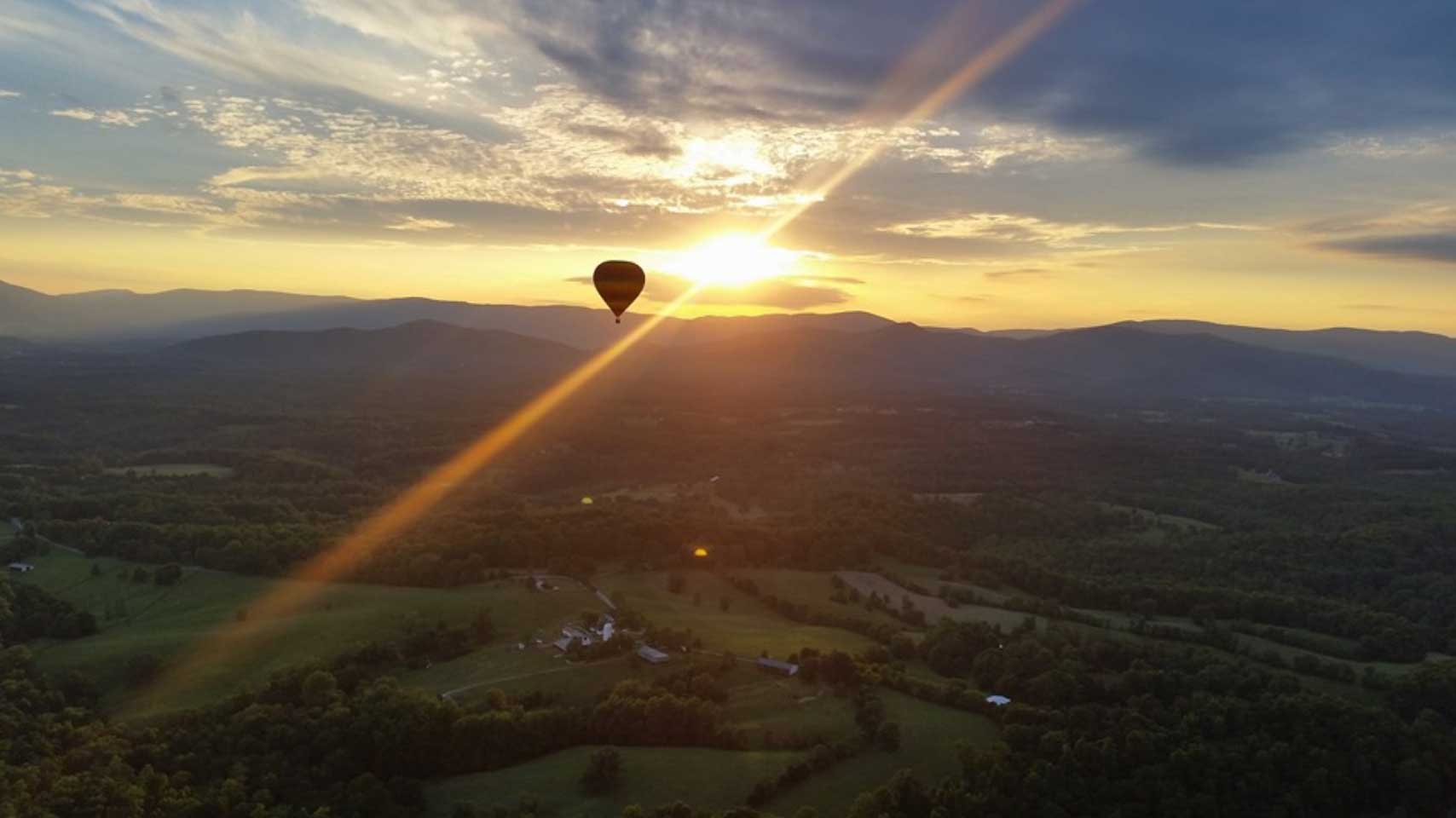 A balloon silhouetted against the sun above Virginia's rolling countryside