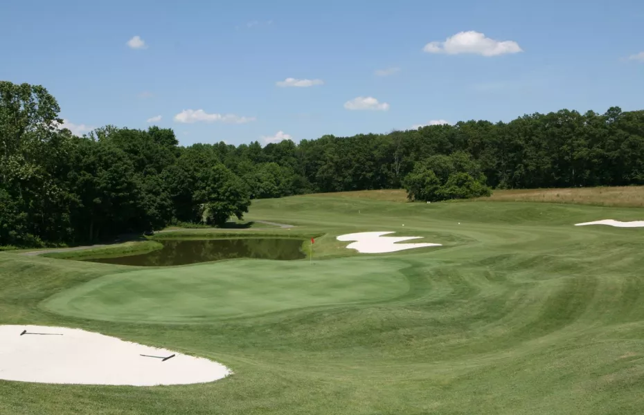 A green at Sycamore Creek bordered by a pond and bright bunkers